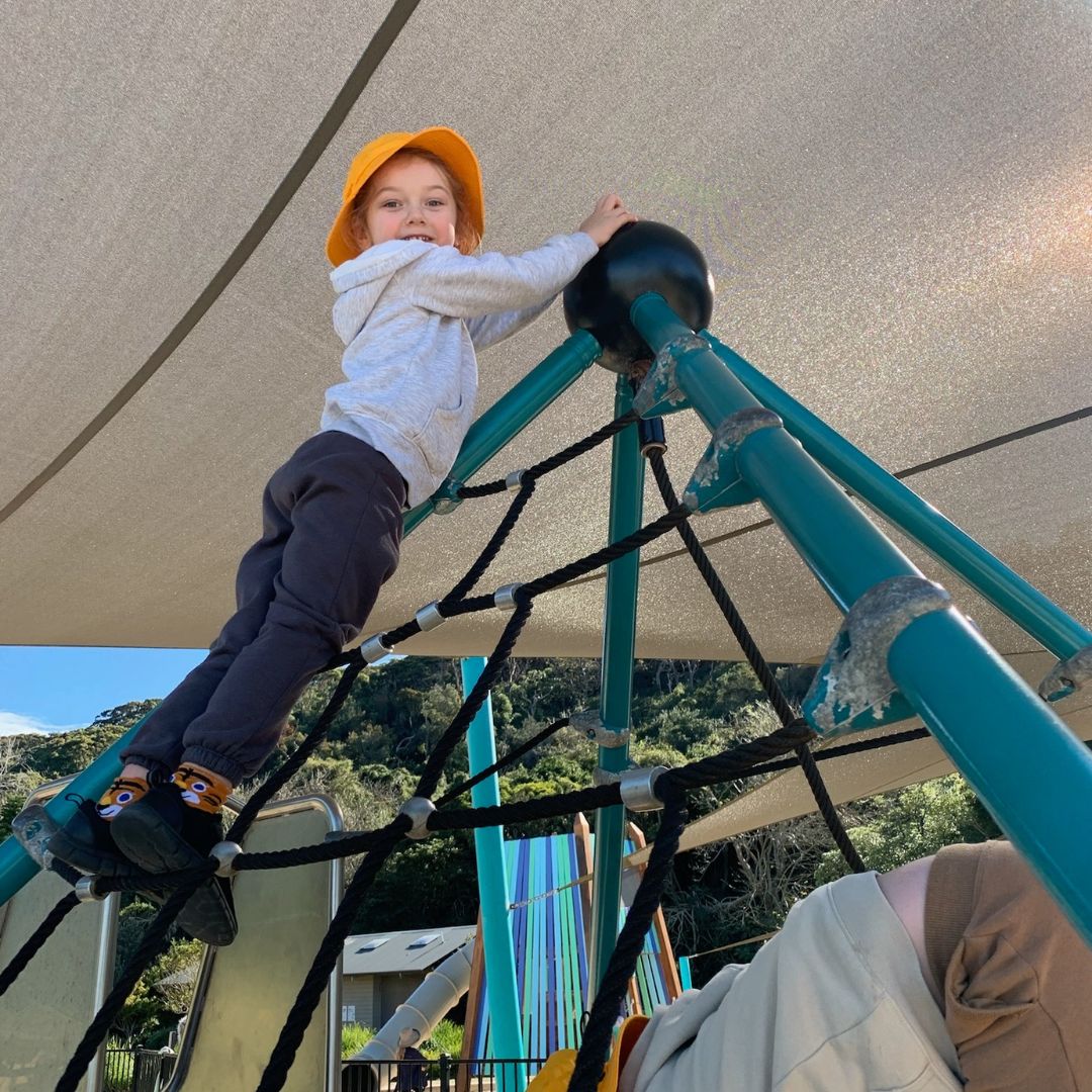 Child in yellow hat at the top of a climbing frame